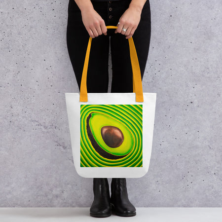 white tote bag with image of a sliced avocado radiating green and yellow bands of color