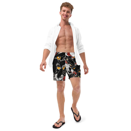Man wearing a white shirt over black swim trunks with colorful black panther tattoo heads designs on a white background
