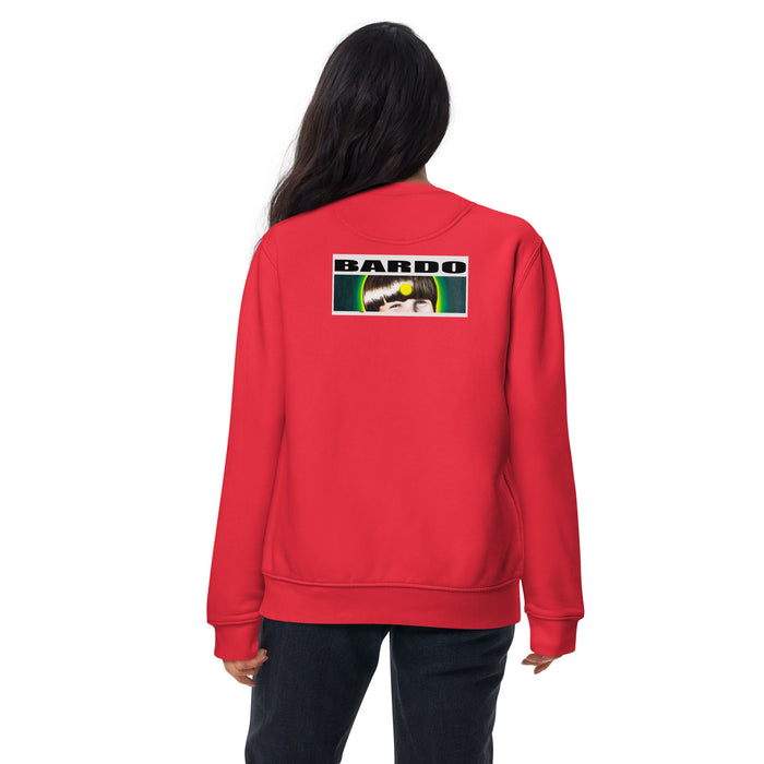 A woman viewed from the back wearing a bright red sweatshirt with a rectangular graphic print on the upper back. The graphic contains the logo'BARDO' in white letters above a green, white, and black image.