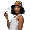 Woman wearing a colorful bucket hat holding sunglasses on a white background