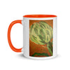 white and orange coffee mug with image of artichoke with colorful lines around it in reds and greens.