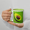 Mug with a psychedelic avocado design held by a hand against a light gray background