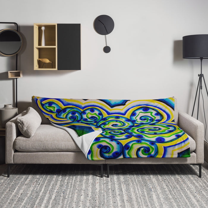 Colorful spiraling aquatic patterned blanket draped over a gray sofa in a modern living room.