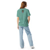 Woman wearing a green t-shirt with a red geometric design on a white background with bardo kid logo on the upper middle back
