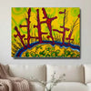 A colorful abstract wall art print hanging above a white sofa in a living room setting. The artwork features stylized red tree-like forms over a bright yellow background with green and blue lower sections.