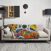 Colorful, psychedelic, abstract patterned blanket on a gray sofa in a modern living room.