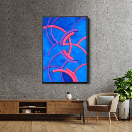 A framed abstract art print featuring vibrant blue, pink, and purple curved lines, displayed on a textured gray wall above a wooden console table in a modern living room setting.