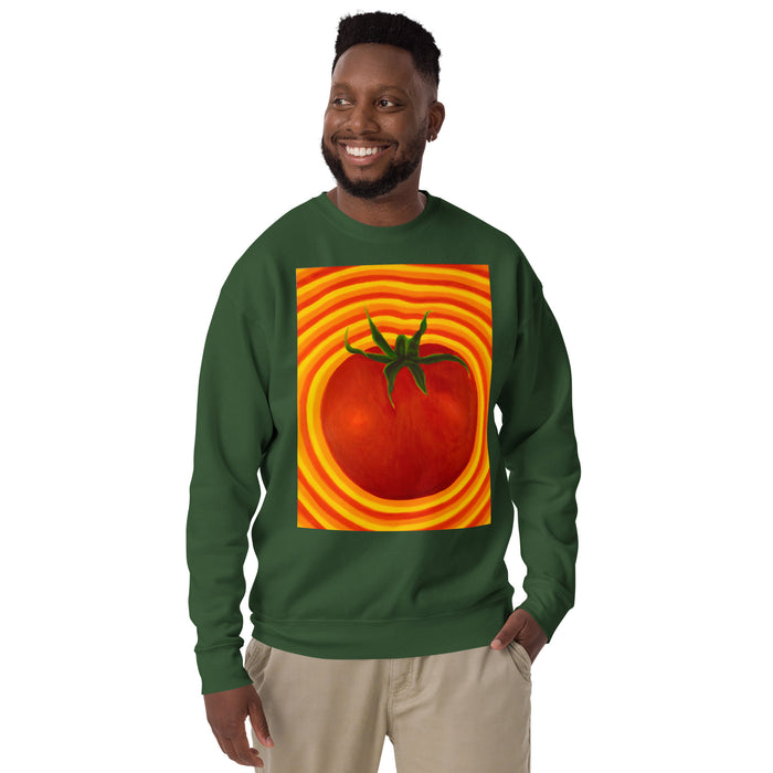 A man wearing a dark green crewneck sweatshirt with a large graphic print of a red tomato inside concentric orange and yellow rings, paired with beige pants, against a plain white background.