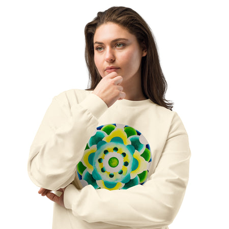 A woman with dark brown hair wearing a cream-colored sweatshirt with a colorful circular mandala graphic on the front, posed against a solid white background.