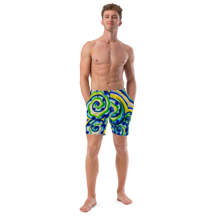 young man wearing shorts with an all over print of watercolor circular art in greens and blues