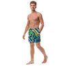 young man wearing shorts with an all over print of watercolor circular art in greens and blues