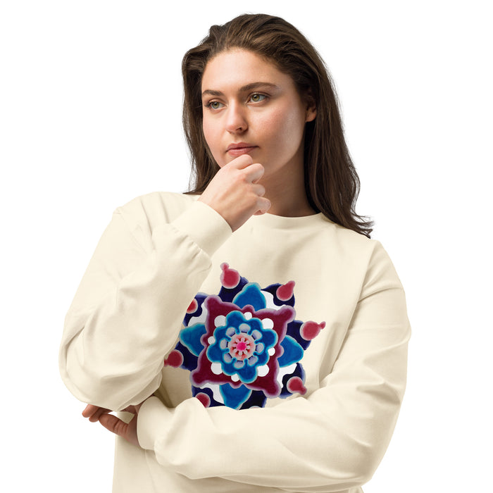 woman wearing a a beige long sleeve t-shirt featuring original watercolor art of a mandala made up of magenta, turquoise, and maroon circular forms.