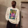 man wearing a beige long sleeve t-shirt with original art depicting a pine cone with dangling octopus tentacles, elk antlers, and a Tibetan halo in front of a stormy lightning filled sky.