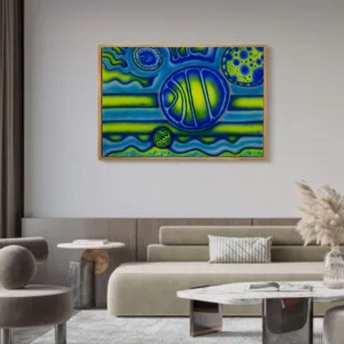 A framed abstract art print featuring vibrant blue and green organic patterns, displayed on a light gray wall above a modern beige sofa in a styled living room.