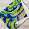 Colorful spiraling aquatic patterned blanket draped over a gray sofa in a modern living room.