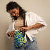 Woman holding a colorful bag with aqua watercolor design against a plain background