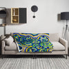 Colorful spiraling aquatic patterned blanket draped over a gray sofa in a modern living room.