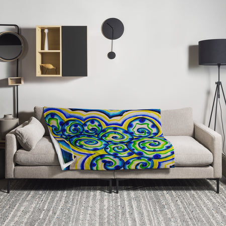 Colorful spiraling aquatic patterned blanket draped over a gray sofa in a modern living room.