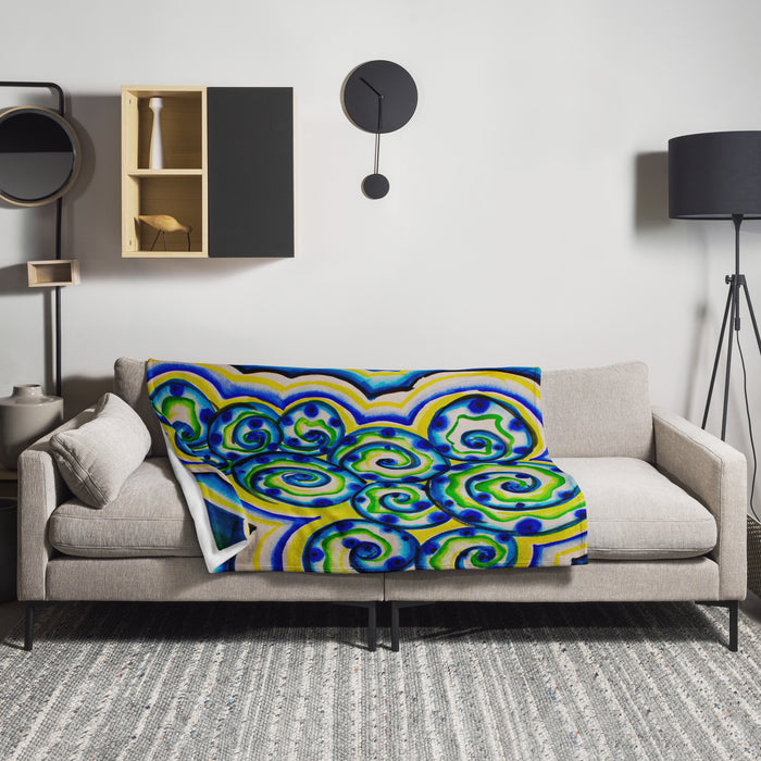 Colorful spiraling aquatic patterned blanket draped over a gray sofa in a modern living room.