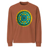 a light brown long sleeve t-shirt with circular original art of a turquoise geometric flower surrounded with squiggly lines on a mustard yellow backround.