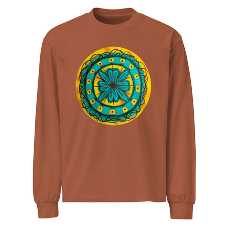 a light brown long sleeve t-shirt with circular original art of a turquoise geometric flower surrounded with squiggly lines on a mustard yellow backround.